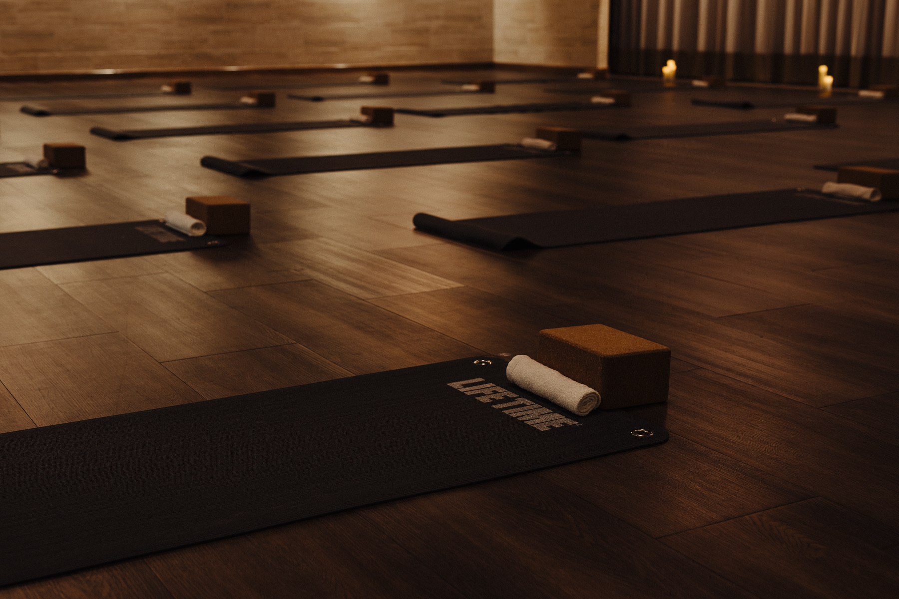 Candlelit yoga studio at Life Time, mats and blocks laid out on a dark wood floor